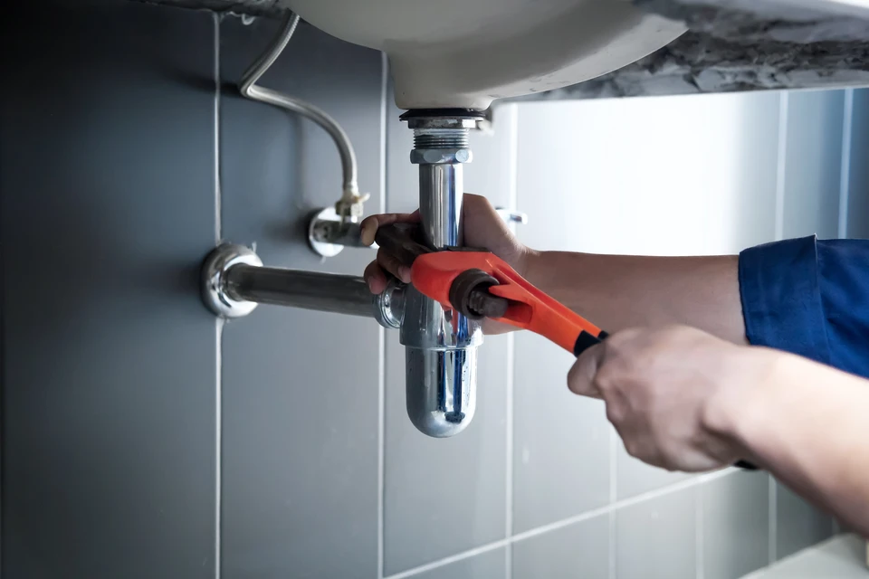 Plumber utilise une clé pour réparer les tuyaux d'eau sous l'évier Il y a de l'entretien pour réparer la fuite d'eau dans la salle de bain