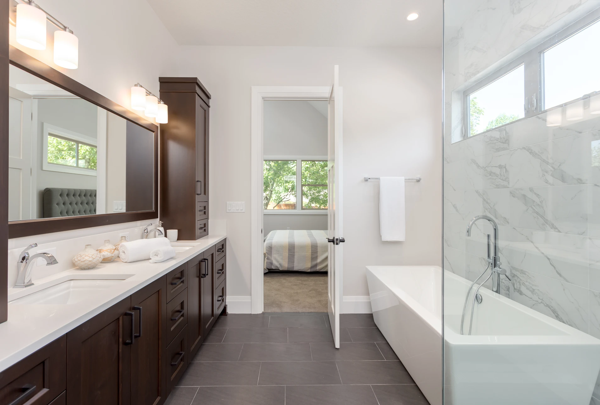 Salle de bain moderne avec double vasque, meuble-lavabo en bois foncé, baignoire îlot blanche et douche à l'italienne
