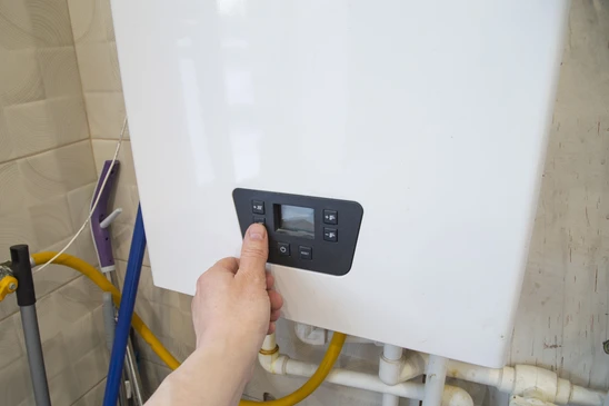 Technicien chauffagiste professionnel de sexe masculin en intervention d'urgence à domicile, effectuant le diagnostic d'une chaudière murale gaz défaillante dans un intérieur résidentiel. Le technicien utilise un outil de diagnostic professionnel ou effectue une vérification manuelle des connexions. La scène se déroule dans un environnement domestique réaliste, montrant l'interaction du professionnel avec l'équipement. La composition doit transmettre la réactivité, le professionnalisme et la confiance.