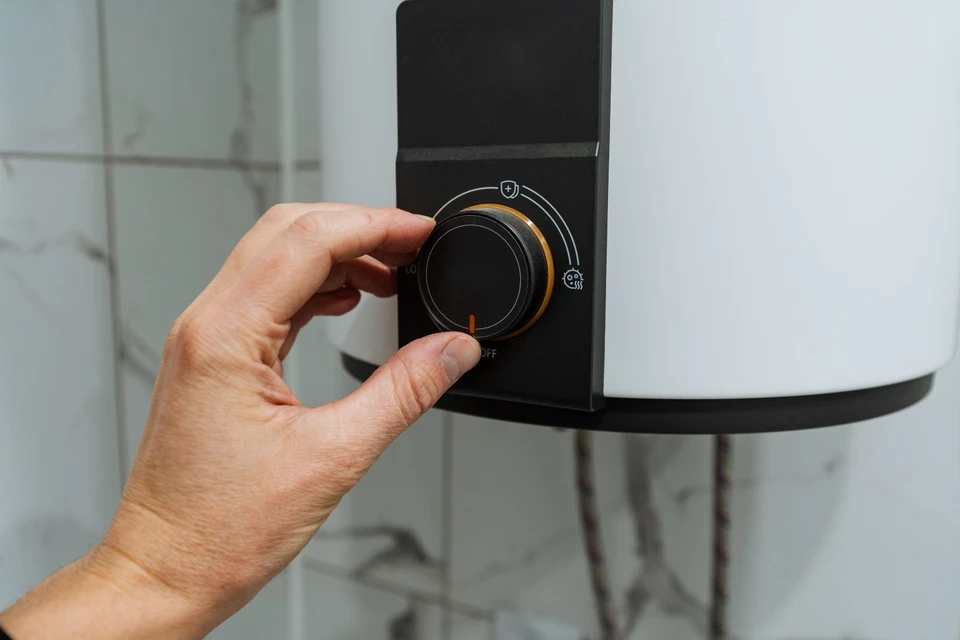 Un technicien en salopette ajuste une vanne sur une installation de chauffage en sous-sol