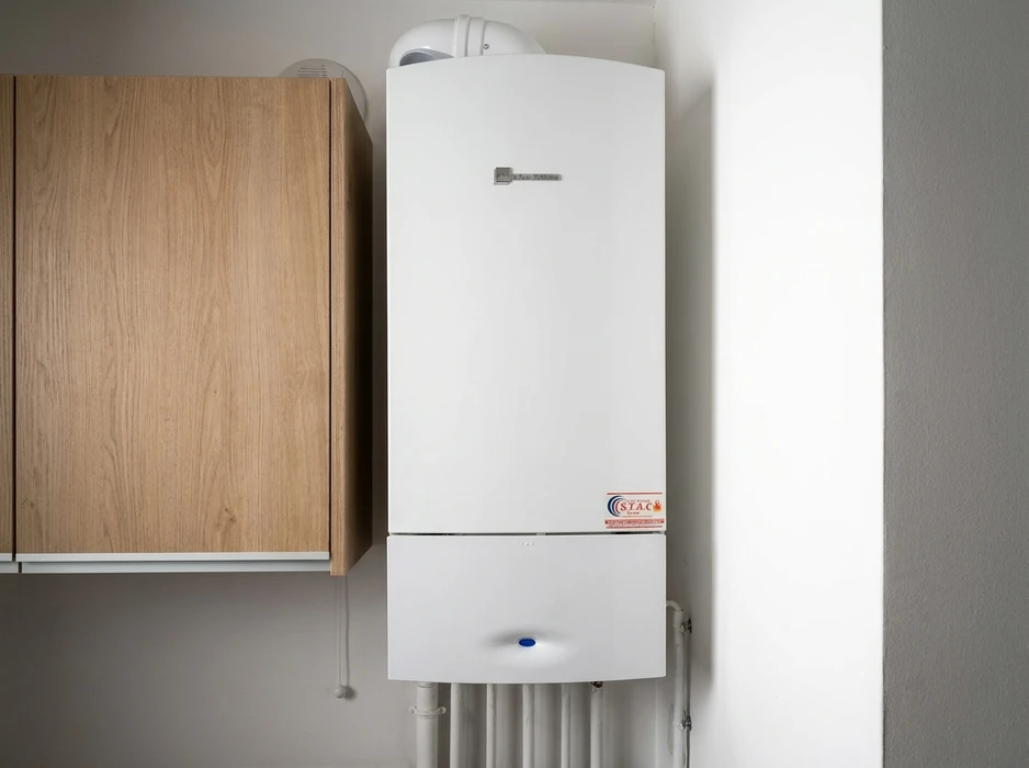 Installation de plomberie intérieure avec tuyauterie en cuivre rouge fixée au mur par colliers métalliques galvanisés
