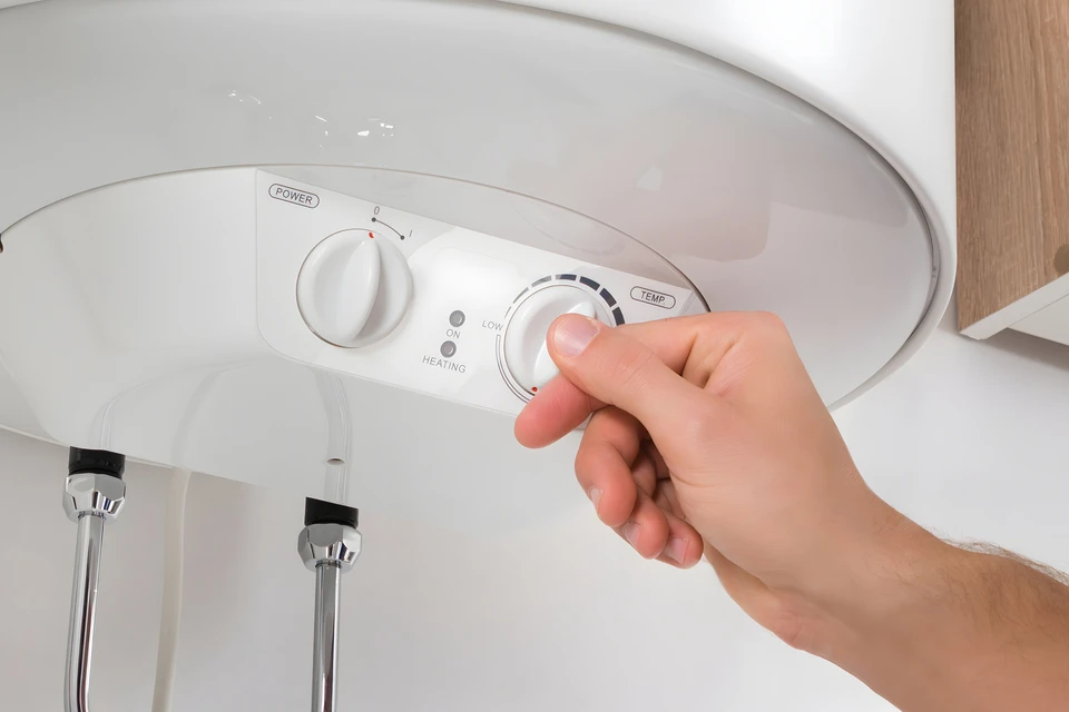 Plombier en combinaison bleue utilisant une clé à chaîne jaune pour serrer un raccord sous un lavabo de salle de bain
